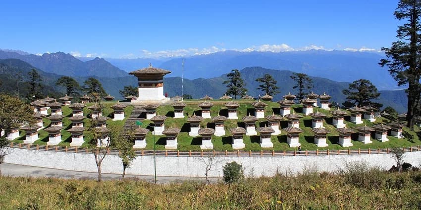 The one hundred and eight white chortens on Dochula Pass with prayer flags and forested ridges