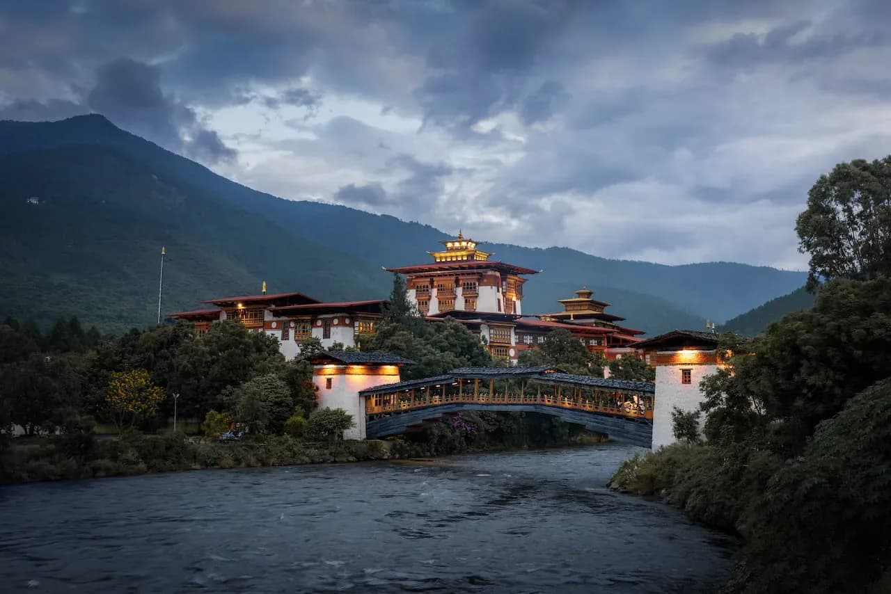 The white walls of Punakha Dzong rising above the river with forested hills behind it